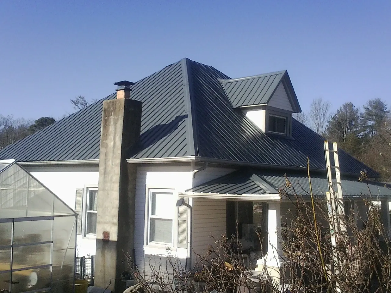 Dark blue standing seam metal roof on a white farmhouse with dormer — Slate & Tile Roof Repair by Roofing Brothers in Artemas