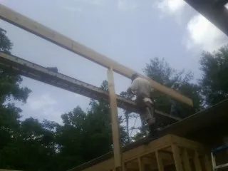 Carpenter setting a ridge beam over a new addition frame — Ice Dam Removal by Roofing Brothers in Artemas