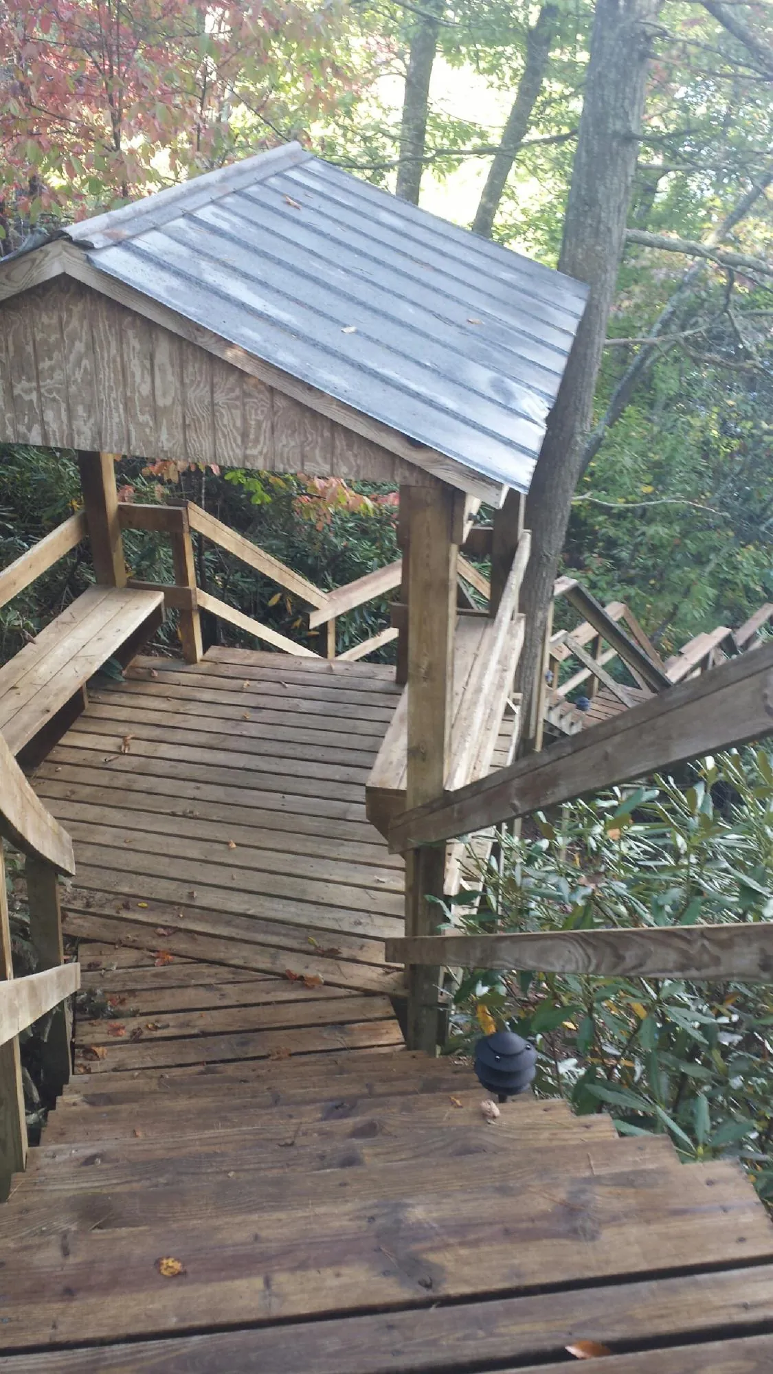 Metal roofed shelter over wooden steps on a wooded walkway — Skylight Repair & Installation work by our crew in Artemas