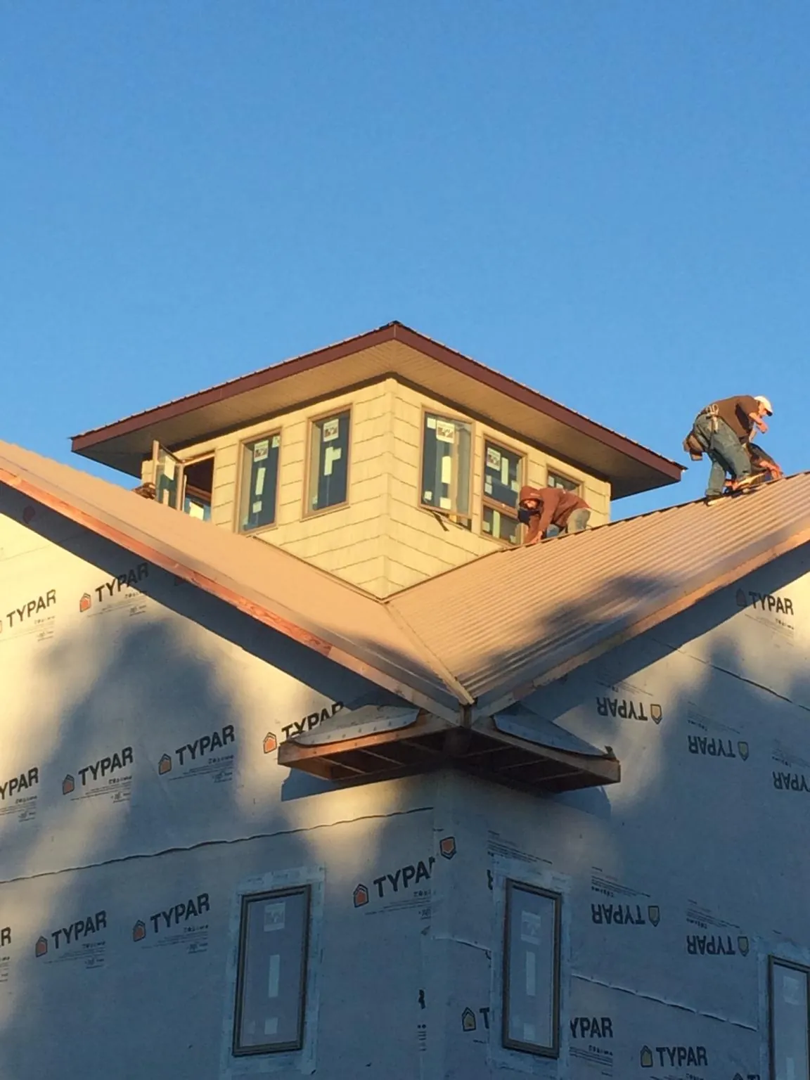 Roofers working around a rooftop cupola on a new metal roof at sunset — Roof Waterproofing in Artemas by Roofing Brothers